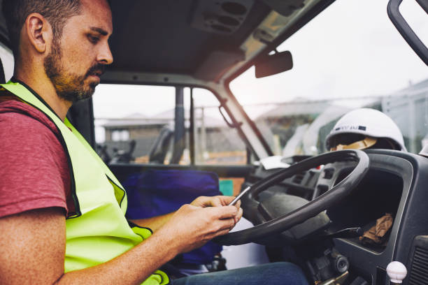 SydneyConstruction.
Construction industry worker texting on the phone inside a truck.